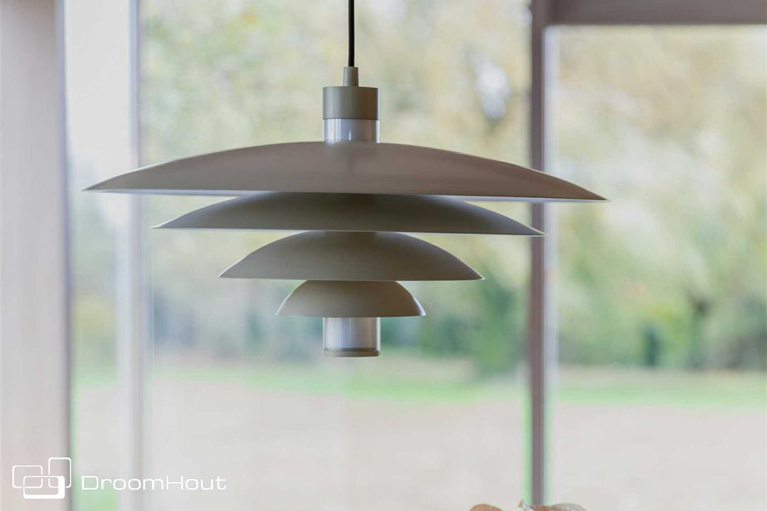 Cole hanglamp van Zuiver in beige met gelaagde metalen kap, hangend boven een eettafel